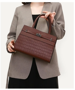 Front view of model holding a dark brown croc-embossed tote bag with flap and twist lock