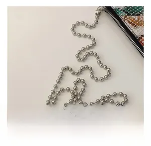 Detail of silver ball chain and premium snakeskin texture on a luxury crossbody bag