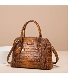 Detail of dark brown crocodile embossed crossbody bag with gold hardware and padlock