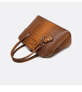 Detail of brown crocodile pattern handbag featuring a metal H charm and top handle structure