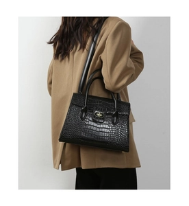 Detail of black crocodile pattern leather tote bag shown on model with shoulder strap