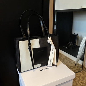Minimalist black and white canvas tote bag with leather trim and decorative silk ribbon