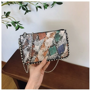 Close-up of snake skin pattern texture with silver bead trim on a chain shoulder bag