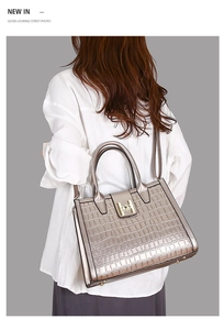 Detail of champagne gold tote bag with crocodile texture and metallic H buckle clasp