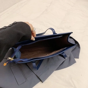 Deep blue faux leather tote bag with gold zipper and spacious interior 45-degree view