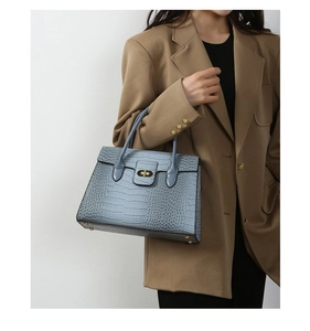 Side view of woman in camel blazer carrying a light blue crocodile embossed tote bag