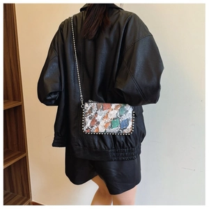 Detail of colorful snakeskin crossbody bag with silver beaded trim and metal chain strap
