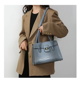 Detail of blue crocodile pattern tote bag with gold twist lock and leather handles