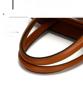 Macro shot of reinforced stitching and brown leather handle on a stylish tote bag