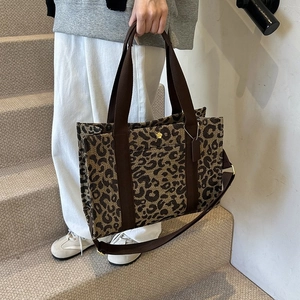 Detail of trendy leopard print tote bag with brown fabric handles and gold flower logo
