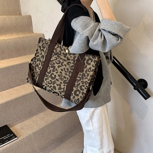 Close-up of leopard print tote bag with brown straps and detachable shoulder strap detail
