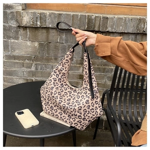 Detailed close-up of leopard print canvas handbag with black zipper and strap in natural light