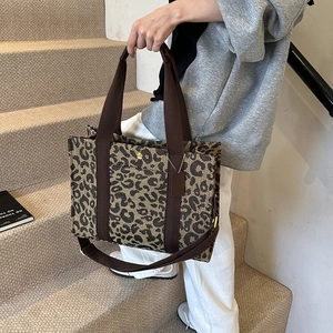 Detail of leopard print tote bag with brown canvas straps and detachable shoulder strap