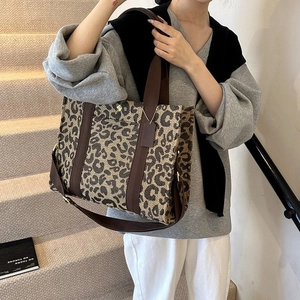 Detail of leopard print tote bag with brown woven straps and adjustable shoulder strap
