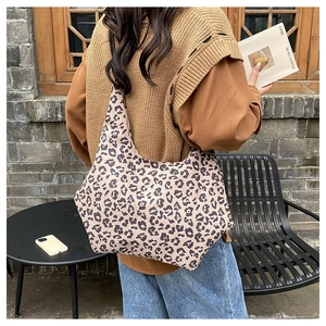Leopard print canvas hobo bag shown worn by a model in a casual outdoor setting