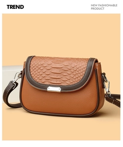 Détail d'un sac bandoulière en cuir marron avec rabat crocodile et fermoir rotatif argenté