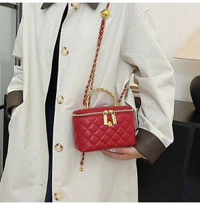 Detail of red quilted patent leather bag with gold metal handle and chain strap