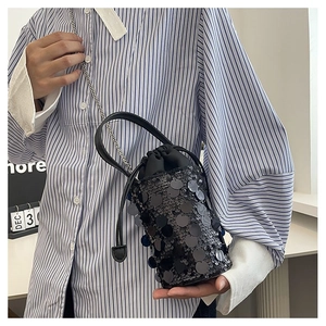 Detail of black sequined bucket bag featuring leather handle and silver metal chain strap