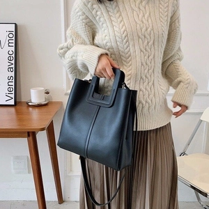 Minimalist black quilted crossbody bag with unique square cutout handle and shoulder strap