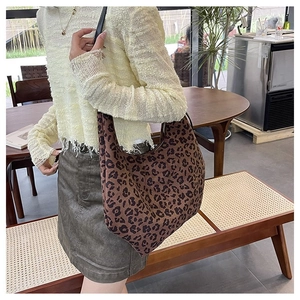 Detailed view of leopard print shoulder bag worn with a casual outfit in an indoor setting