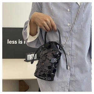 Detail of black sequined bucket bag with drawstring closure and silver chain strap