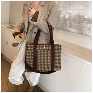 Close-up of large tote bag with houndstooth pattern and elegant gold magnetic buckle detail