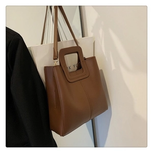 Brown minimalist tote bag with cutout handle and slim shoulder strap for women