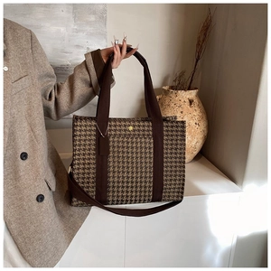 Detail of vintage houndstooth tote bag featuring a golden floral logo and fabric strap