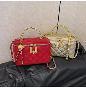 Detail of red and gold quilted square bags with flower charm and metallic handle