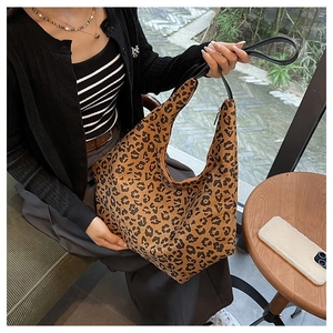 Close-up of leopard print hobo bag worn on shoulder at an outdoor cafe setting