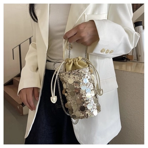 Detail of sparkling sequin bucket bag featuring a drawstring closure and silver chain strap