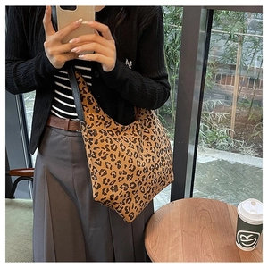 Detailed close-up of leopard print canvas hobo bag with slim black shoulder strap texture
