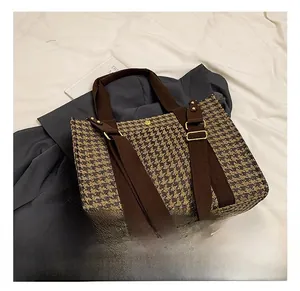 Detailed houndstooth tote texture with brown canvas handle and golden metal buckle accents