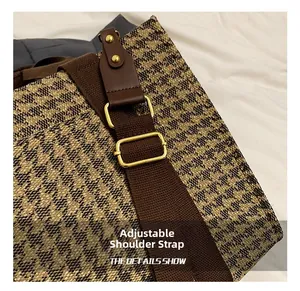Macro detail of adjustable woven shoulder strap with gold metal hardware and brown trim
