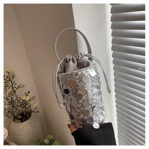Detailed view of silver sequin bucket bag with grey drawstring closure and metal handle