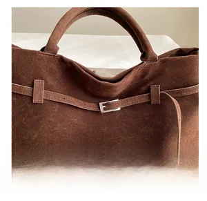 Λεπτομέρεια σκούρας καφέ σουέτ τσάντας με ασημένια μεταλλική αγκράφα και ραφές ακριβείας