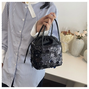Detail of black sequined bucket bag with drawstring closure and chain strap detail