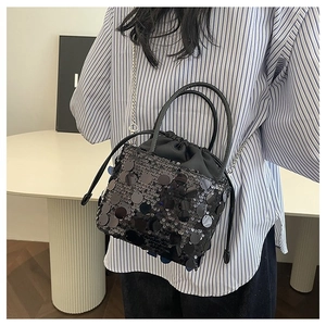 Detail of black sequin bucket bag with silver chain strap and shiny metallic discs