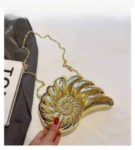 Détail d'une pochette dorée en forme de coquillage avec motif nautile et chaîne