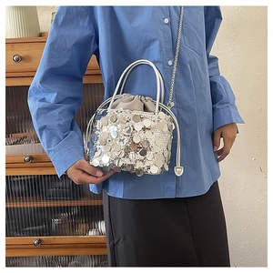Detail view of silver sequin bucket bag with drawstring closure and chain strap