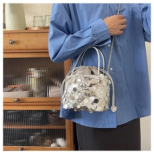 Detail of silver sequin bucket bag with drawstring closure and metallic chain strap
