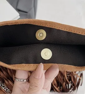Detail of the golden magnetic snap closure and premium brown suede texture of the bag
