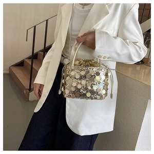Close-up of golden sequin bucket bag with drawstring closure and metallic chain strap