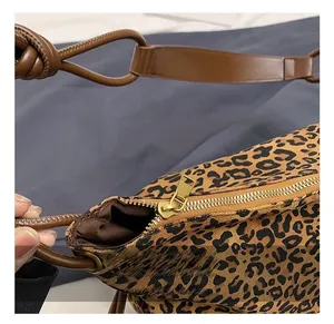 Détail du sac en nylon léopard avec fermeture éclair dorée et bandoulière en cuir brun