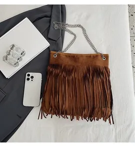 Detailed view of brown suede fringe shoulder bag with thin silver chain strap and tassels