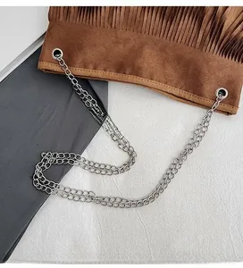 Detail of silver chain strap attachment on a brown fringe suede crossbody bag