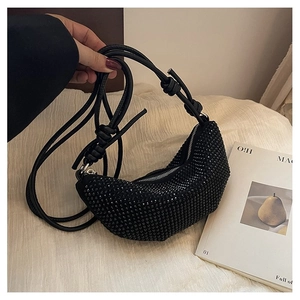 Primer plano detallado de un bolso de media luna con pedrería negra y correa con nudo