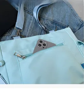Dettaglio della tasca anteriore con zip di una borsa a tracolla azzurra con smartphone