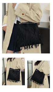 Detailed macro view of black suede shoulder bag featuring long fringe and silver chain strap
