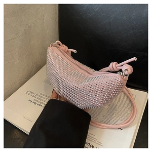 Detalle de cerca del bolso hobo rosa con pedrería y correa fina anudada de diseño